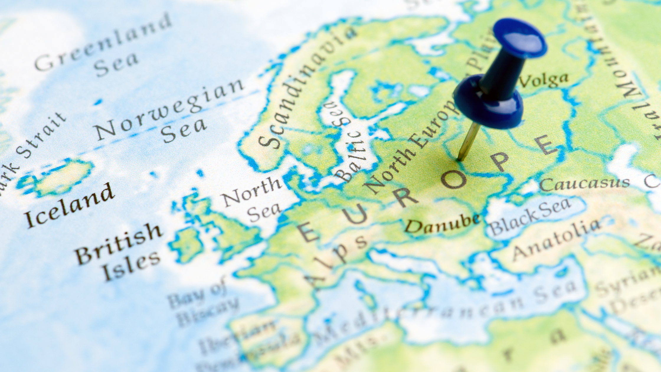 A close-up of a map of Europe with a blue pushpin marking the continent.