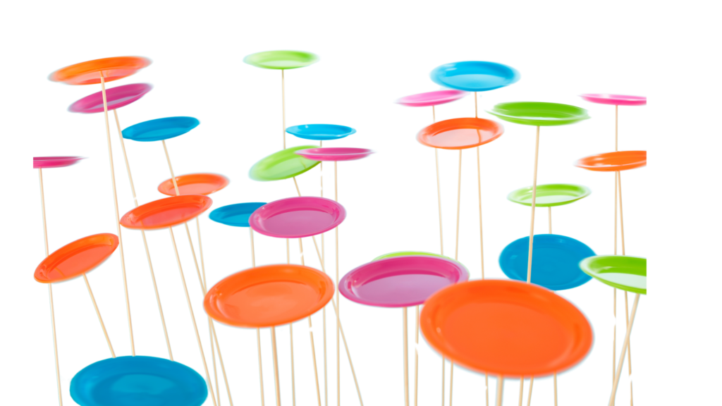 Colourful spinning plates in bright hues of orange, blue, pink, and green balanced on thin sticks against a white background.